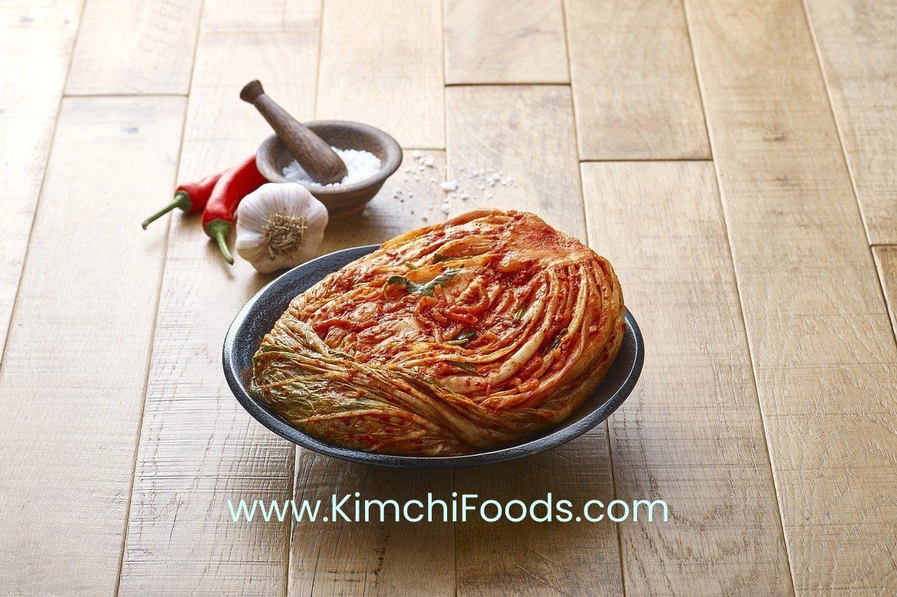 a sweet and delicious kimchi pancake in a pan placed on a wooden table along with a garlic, 2 red chilies and a spice manual grinder